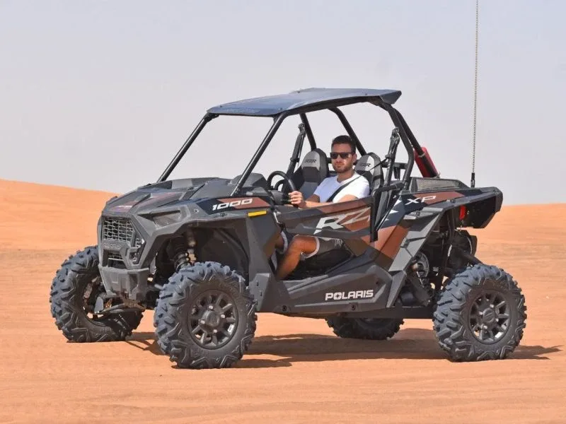 Rear view of the 2 Seater Polaris RZR 1000cc buggy parked on a red sand dune in Dubai