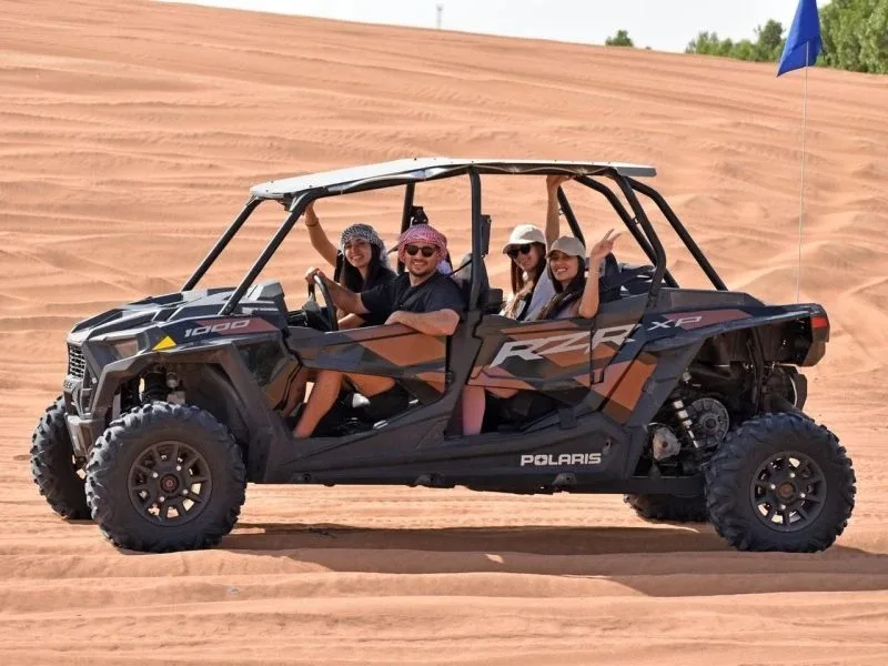 Family of four riding a Polaris RZR dune buggy across the dunes in Dubai