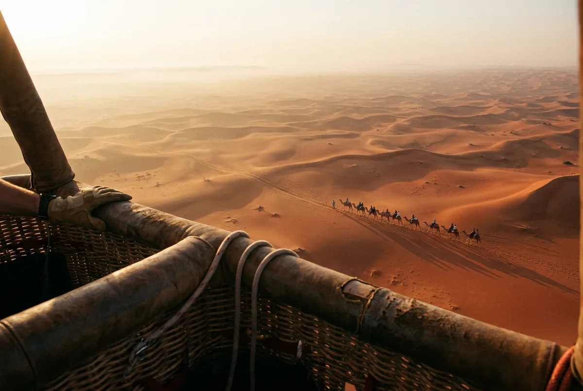 Camels grazing on the desert floor as seen from a hot air balloon basket over Dubai