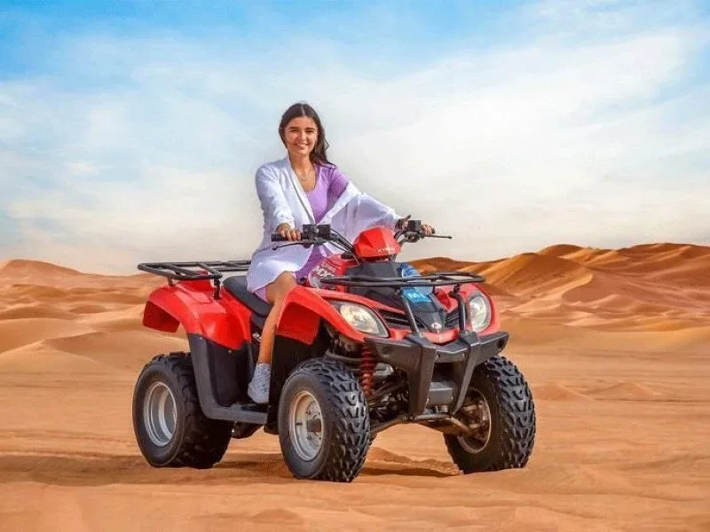 Single seater quad bike rider crossing open red sand dunes in the Dubai desert